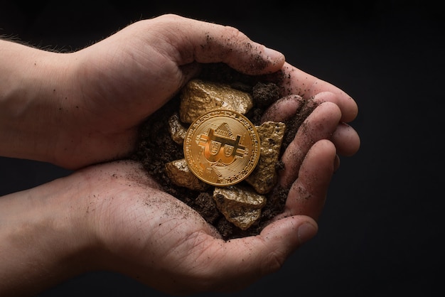 Gold nuggets with a bitcoin in the hands of the miner