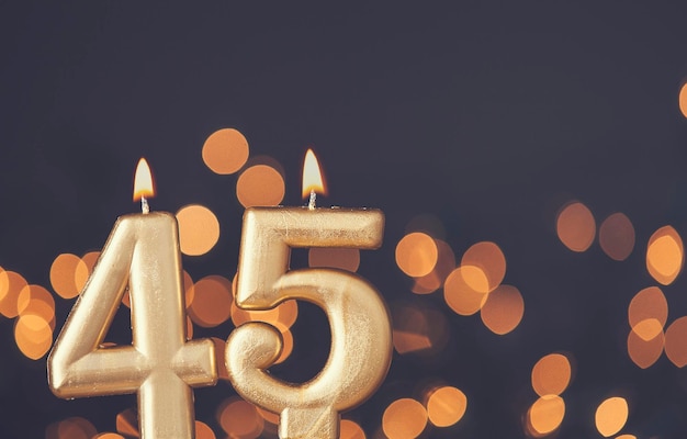 Gold number 45 celebration candle against blurred light background