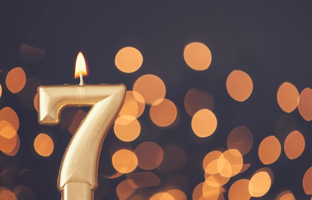 Photo gold number 7 celebration candle against blurred light background