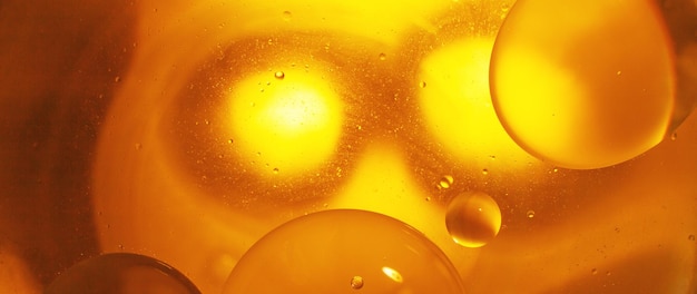 골드 오일 거품은 주황색 물 매크로 추상 빛나는 노란색 배경의 원을 닫습니다.