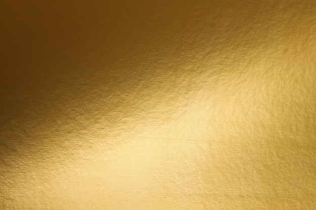 A gold paper that is textured and has a light shining on it.