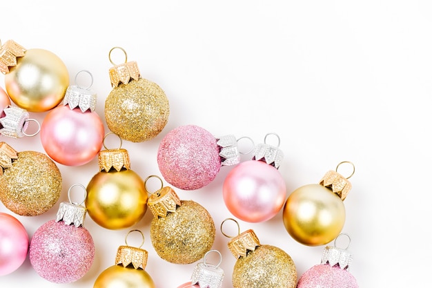 ワイトの背景にゴールドとピンクのクリスマスボール。フラットレイ、上面図