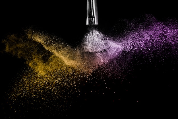 Photo gold and purple powder splash in black background