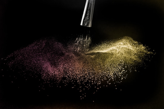 Gold and purple powder splash in black background