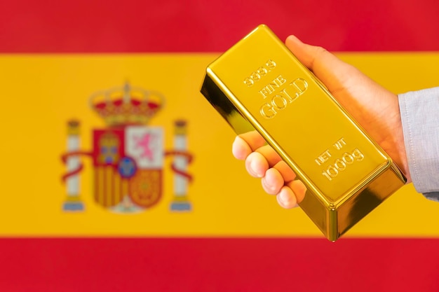 Gold reserve of the spain concept gold bar in hand on flag spain background