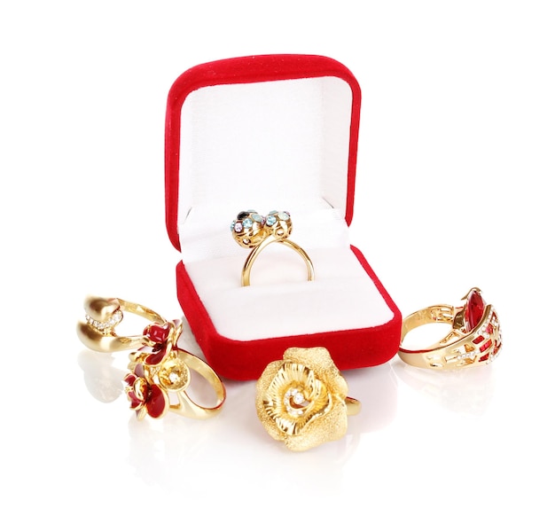 Gold ring with blue black lilac and clear crystals in red velvet box and four golden rings isolated on white