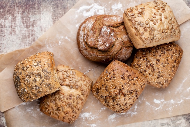 Gold rustic crusty loaves of bread and buns on wooden table. Still life captured from above top view, flat lay.