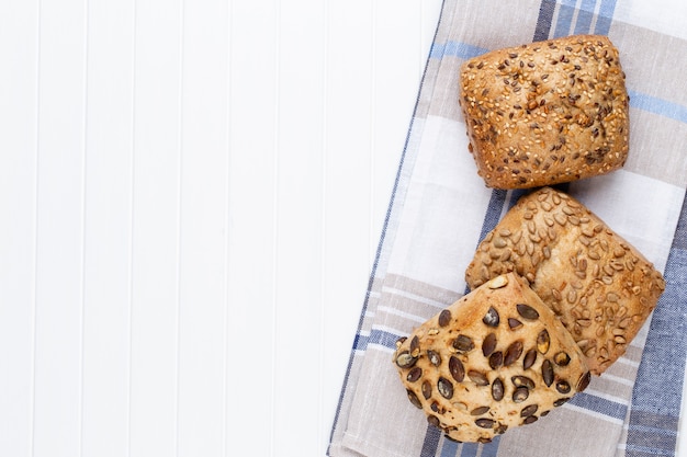 Gold rustic crusty loaves of bread and buns on wooden.