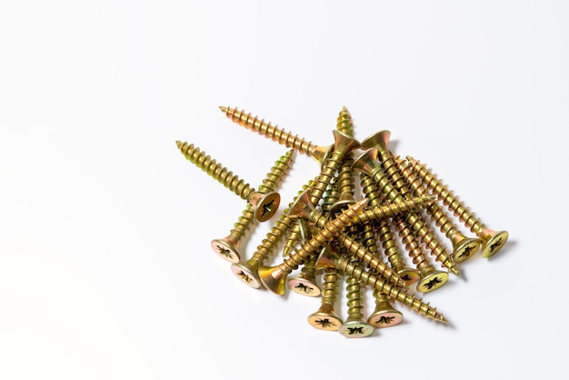 Gold screws scattered randomly on a white surface. Yellow zinc head screws