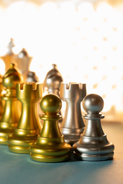 Gold and silver chess pieces on a background of light