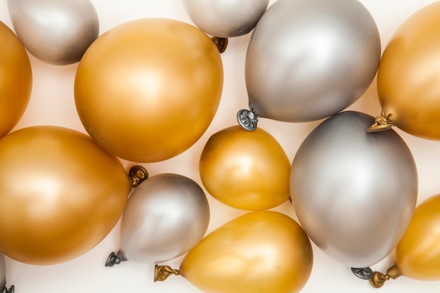 Gold and silver party celebration balloons on a plain background