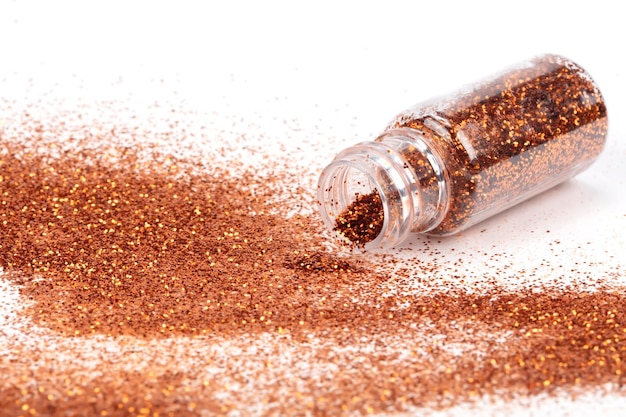 Gold sparkles pour out of the bottle Glitter is pouring from a bottle on a white background