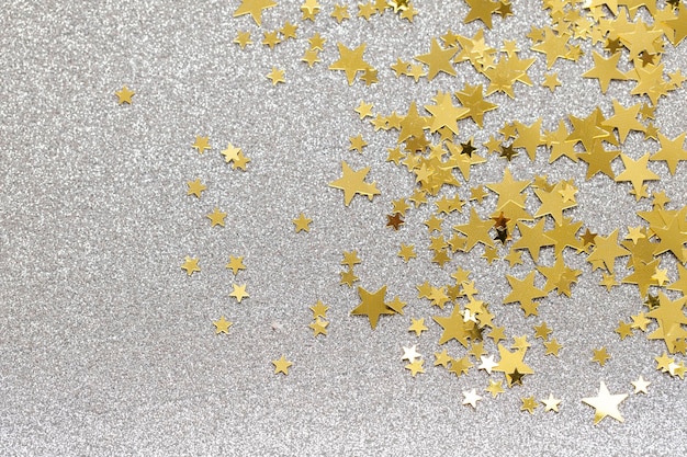 Gold star confetti on a silver glitter background festive holiday background