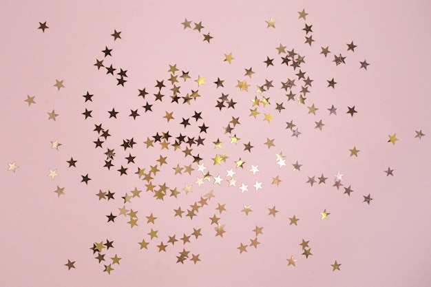 Foto glitter a forma di stella d'oro su sfondo rosa. stile piatto per vacanze, compleanni, matrimoni, capodanno, natale, feste, celebrazioni