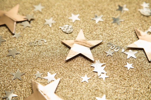 Gold star sparkle party confetti on a gold glitter background