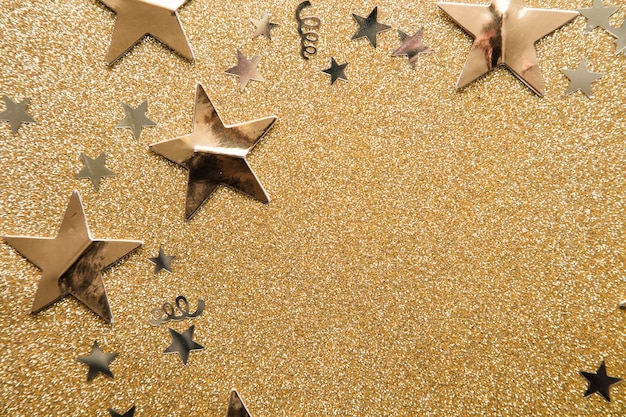 Gold star sparkle party confetti on a gold glitter background