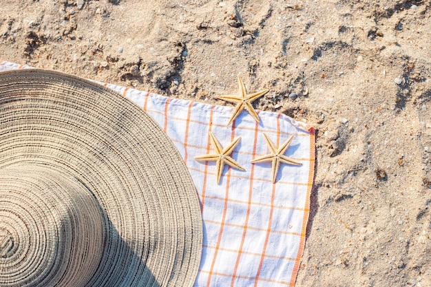 Gold starfish hat on the sandy beach Top view flat lay