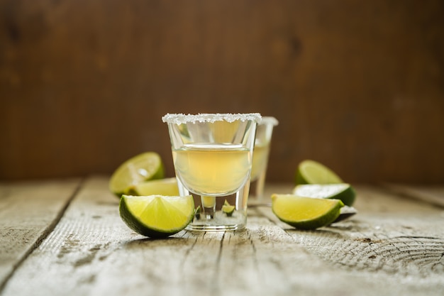 Gold tequila shots on rustic wood 