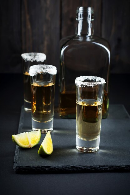 Gold Tequila with lime and salt on a dark surface. Selective focus.