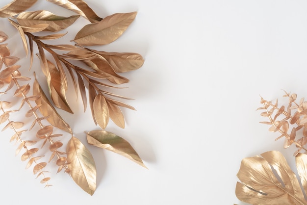 Gold tropical palm leaves Monstera on white background Flat lay