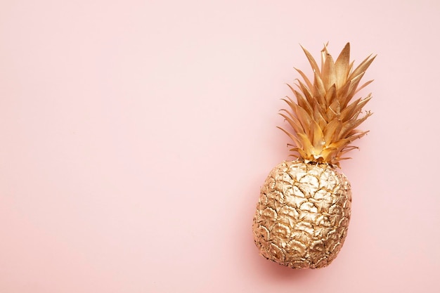 Gold tropical pineapple on a pastel pink background Flat lay summer background