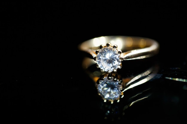 Gold wedding ring on black glass