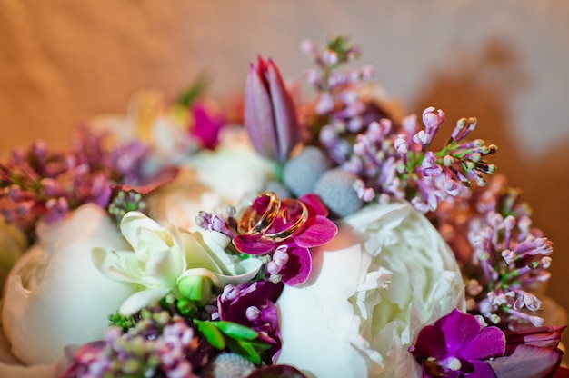 Gold wedding rings on a background of flowers, close up.