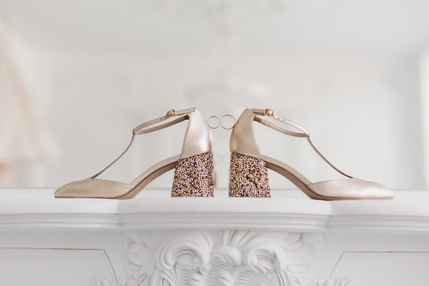 Gold wedding rings between the bride's wedding shoes