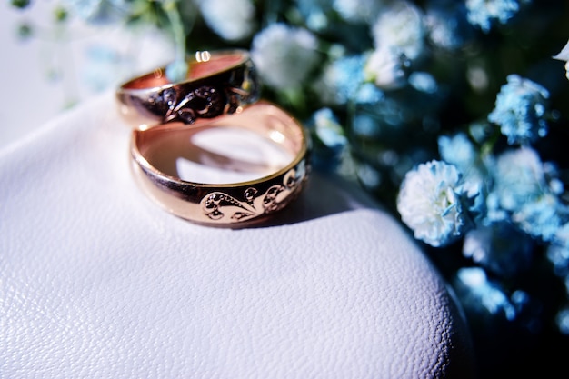 Gold wedding rings on the bride's white shoe and a beautiful bouquet of blue gypsophila in the background. details, wedding traditions. close-up.