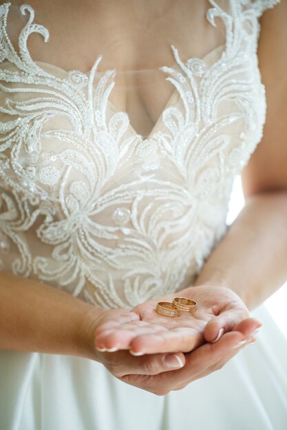 Gold wedding rings in the hands of the newlyweds