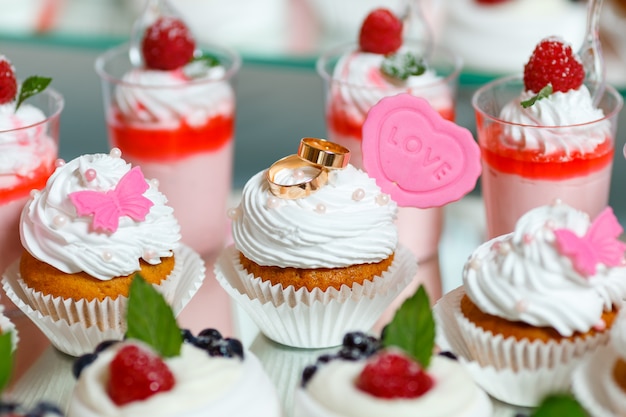 Gold wedding rings lie on the cute cupcakes