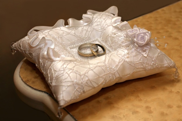 Gold wedding rings lie on a decorative pillow