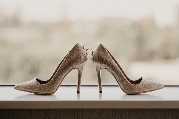 Gold wedding rings between pair of golden high heel shoes