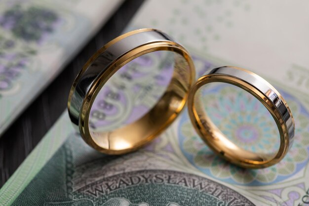 Золотые обручальные кольца, окруженные кучей польских банкнот.