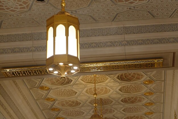 A gold and white ceiling light Lamp inside Grand Mosque in Mecca