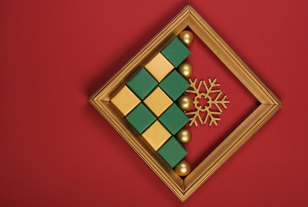 Фото Золотая деревянная рамка с золотыми и зелеными рождественскими украшениями на красном фоне