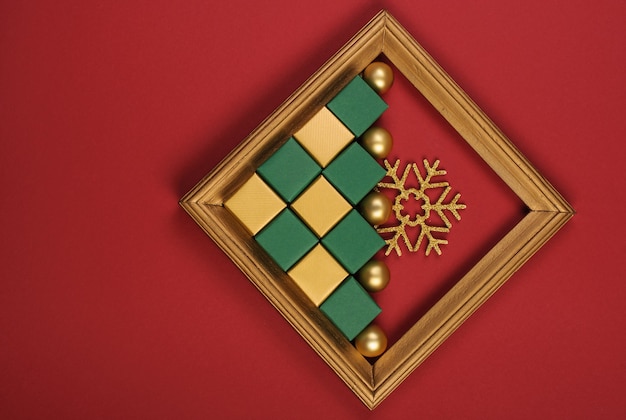 Gold wood frame with gold and green christmas decorations on red backgroun