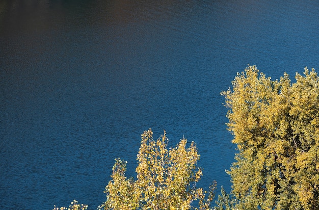 Golden autumn with colourful trees in old flooded quarry. Rocks, lake and yellow trees