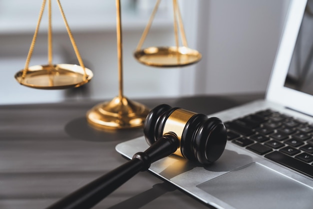 Golden balanced scale and gavel on desk with laptop in law office equility