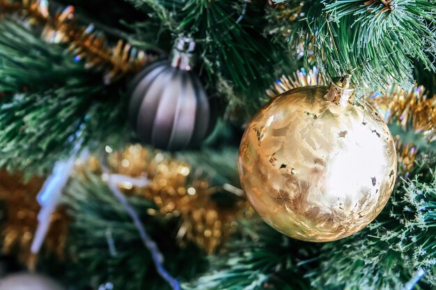 Golden ball on an artificial Christmas tree decorated with a gold garland