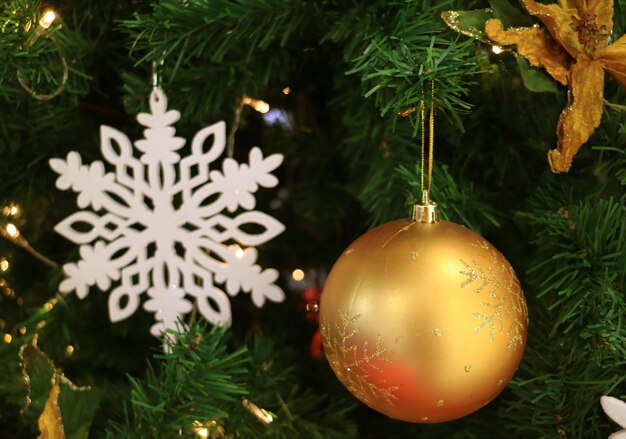 Golden ball shaped Christmas ornament with blurred white snowflake ornament in background