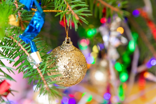 Photo golden ball on a spruce branch decorated for christmas and new year among serpentine and garlands with lights