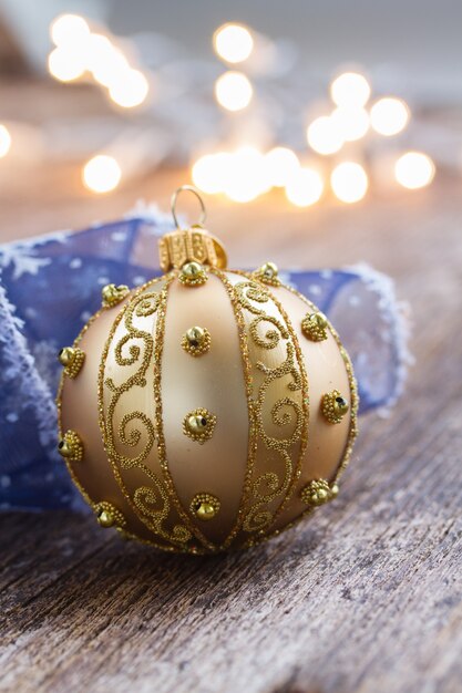 Golden ball with blue ribbon, christmas lights bokeh