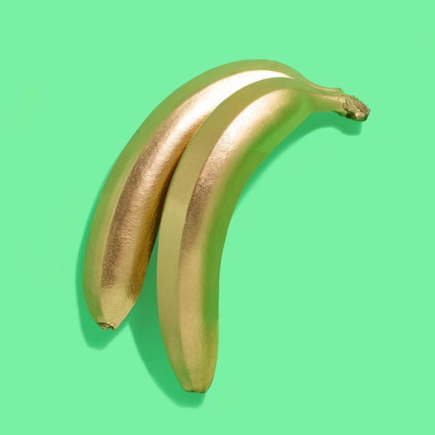 Golden bananas on green background