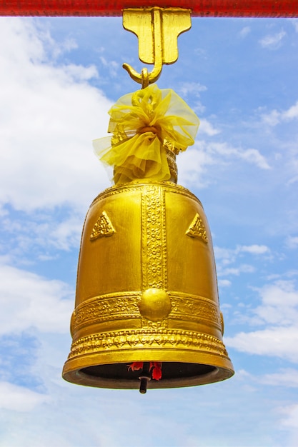 Photo golden bell hang with red iron beams large size with bright sky and cloud