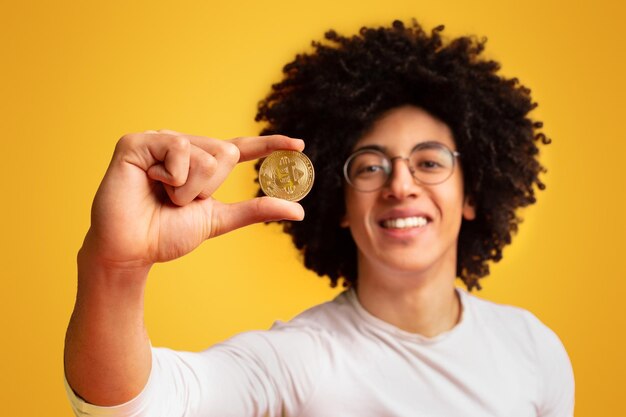 Golden bitcoin in africanamerican man hand closeup