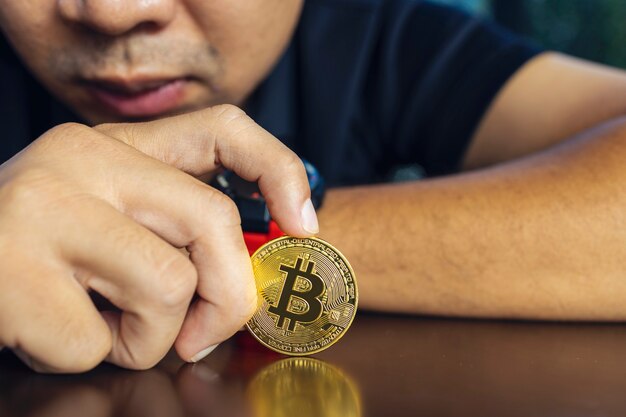 Photo golden bitcoin in a businessman hand on table