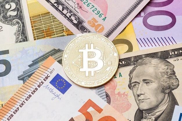 Golden bitcoin coin on us and euro notes. High resolution photo.