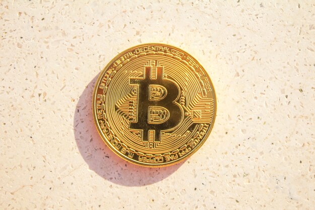 Golden bitcoin coin on white stone background