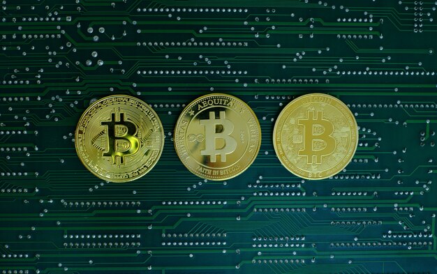 コンピューターの電子回路基板の背景にあるゴールデンビットコイン暗号通貨の新旧バージョン